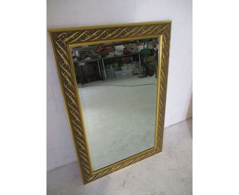 A gilt framed wall mirror with Art Nouveau decoration. Overall size 95cm x 65cm.