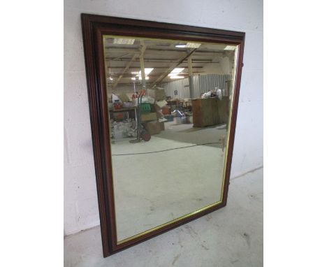 A dark wood framed wall mirror with bevelled edge. overall size 106cm x 90cm