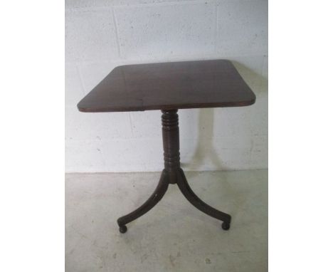 An antique tip up table on turned support with tripod legs