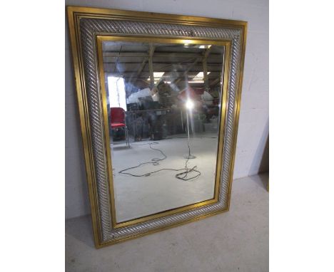 A gilt and silver colour framed wall mirror. Overall size 110cm x 83cm