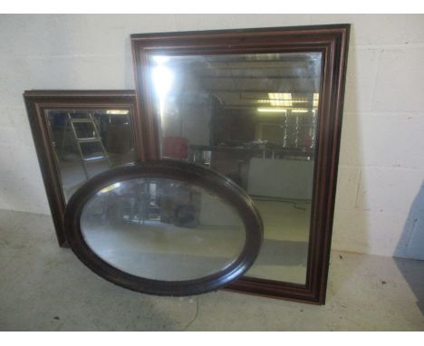 An Edwardian oval mirror 126cm x 88cm, plus two dark wooden framed mirrors. 