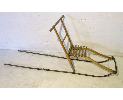 A vintage wooden sled with slatted seat and metal runners