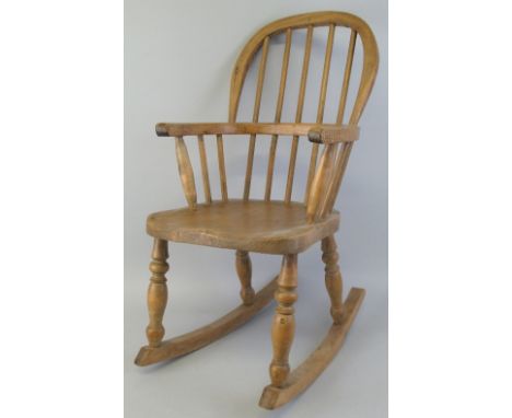 A child's ash and elm rocking windsor chair, with plain stick back and turned arm supports and legs