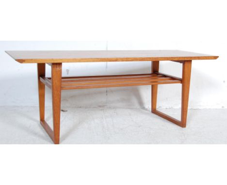 A retro vintage 1970s teak wood coffee table having a rectangular table top with slatted magazine tray underneath raised on s