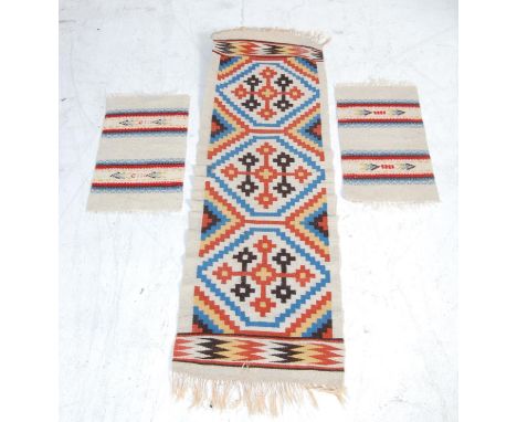 A group of three vintage 20th century Norwegian Scandinavian handwoven wool table runner / wall hanging rugs being decorated 