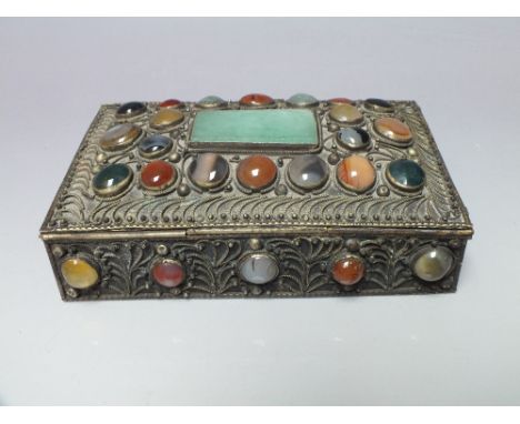 AN ORIENTAL WHITE METAL LIDDED BOX, all over scroll work with inset semi-precious polished cabochon decoration, and a larger 