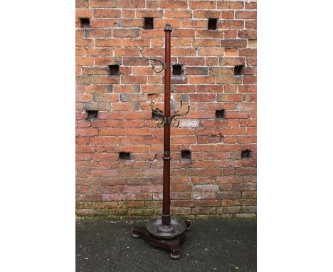 A MID VICTORIAN MAHOGANY CIRCULAR HALLSTAND, the tapered cylindrical column with six decorative brass hooks, carved fluted fi