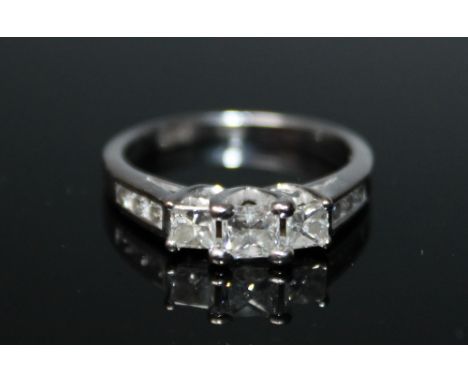 A 14 CARAT WHITE GOLD DIAMOND RING, set with three Princess cut diamonds totalling approx 0.95 carat , with inset brilliant c