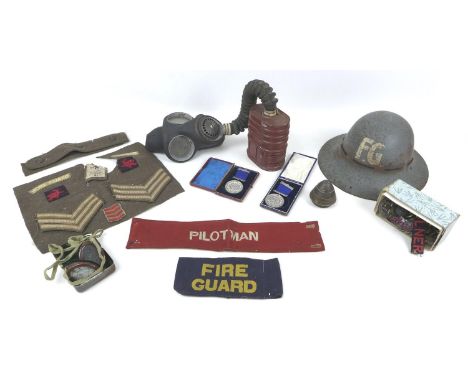 A WWII gas mask, a Fire Guard helmet and arm band, three cap badges, Royal Warwickshire, Northamptonshire, Royal Artillery, a