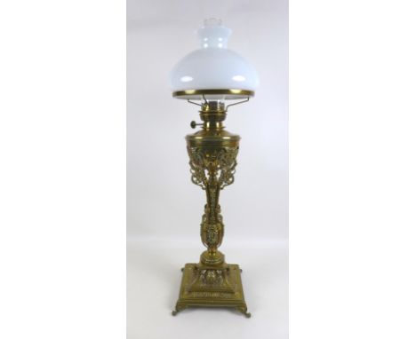 A Victorian brass paraffin lamp, with brass reservoir on a cast floral column, clear glass chimney and white glass shade, on 