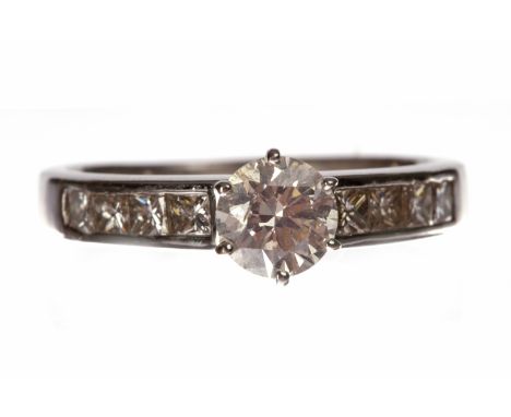 DIAMOND SOLITAIRE RINGwith a six claw set round brilliant diamond of approximately 0.70 carats on channel set princess cut di