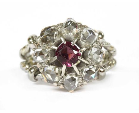 An Edwardian garnet and diamond cluster, later mounted to a two row twisted wire ring shank. A cushion-shaped old cut garnet,