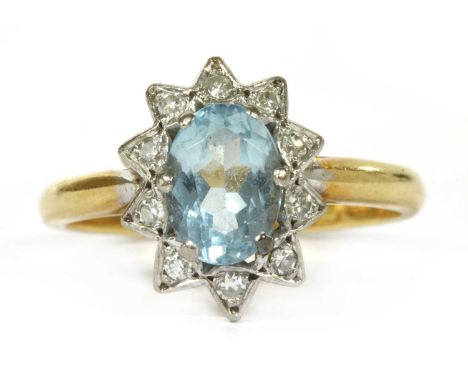 A gold aquamarine and diamond cluster ring, an oval mixed cut aquamarine, claw set to a surround of eight cut diamonds, grain