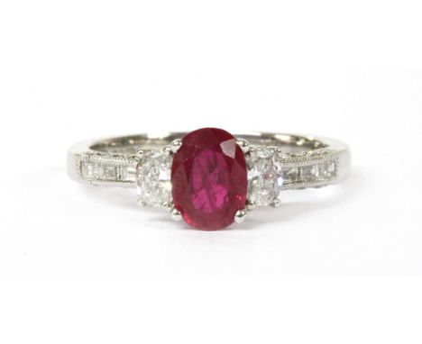 An 18ct white gold ruby and diamond three stone ring, an oval mixed cut ruby, with a stated weight of 0.70ct, claw set to a p