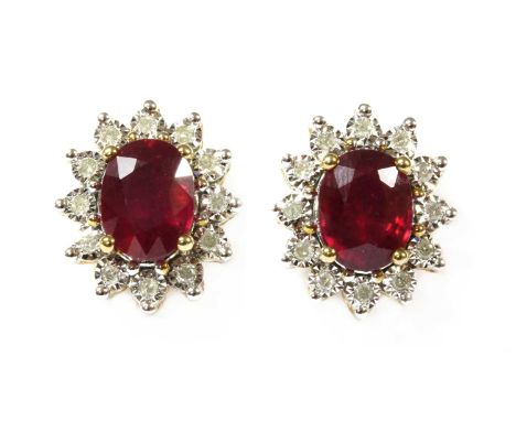 A pair of gold ruby and diamond cluster earrings, an oval mixed cut ruby, fracture filled, four claw set to a surround of bri