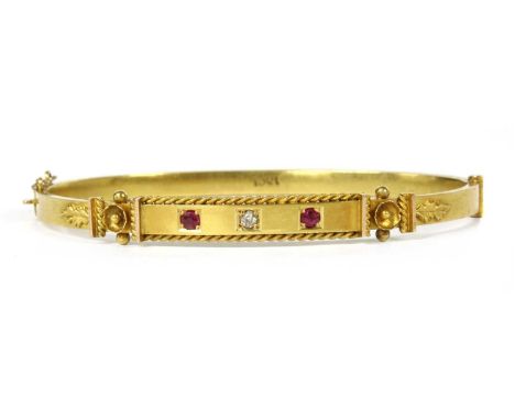 A gold diamond and ruby set oval hinged bangle, an eight cut diamond and two circular mixed cut rubies, grain set to the top 