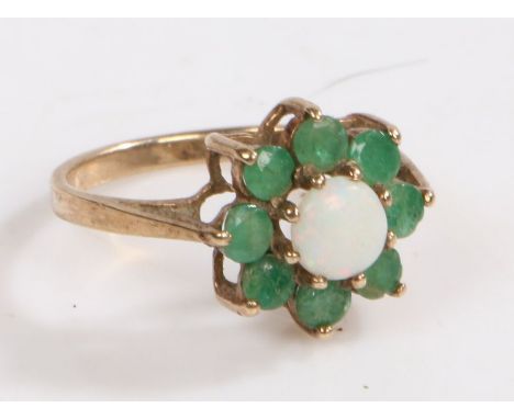 A 9 carat gold, white opal and green stone ring, the head of floral form set with a central cabochon white opal surrounded gr