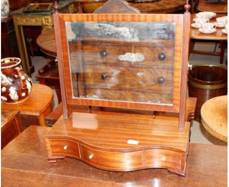 A 19th Century mahogany serpentine fronted swing toilet mirror, the rectangular plate raised on reeded arms surmounted by fin