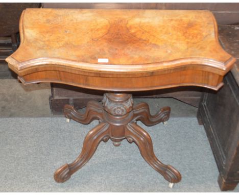 A Victorian walnut serpentine fronted card table, raised on a carved baluster column and quadruple splay, terminating in cast