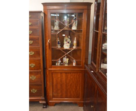 An early 20th Century mahogany floor standing corner cabinet, the upper display shelves enclosed by a glazed panelled door, c