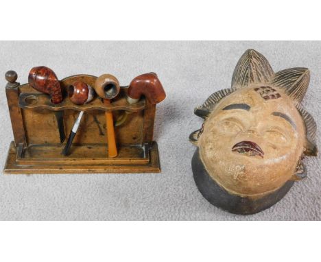 A tribal African Punu Female Okau figure mask and a collection of four Vintage wooden and plastic and metal pipes with pipe s