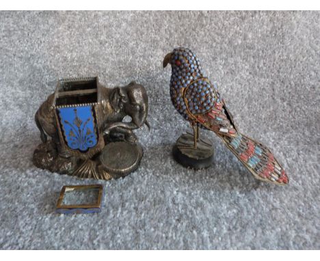 An antique silver plate and blue enamel elephant match holder with gilded details and an Indian metal bird on wooden stand wi