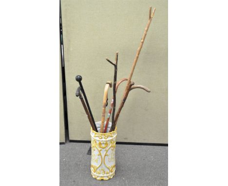 A ceramic stick stand containing various walking sticks, including one with a horn handle