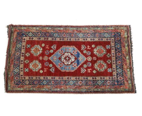 A hand knotted Persian rug, the red fields with central blue medallion within a multi-border 196 x 167.5cm