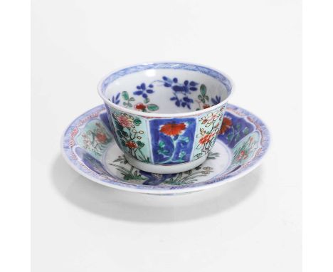 A Chinese wucai tea bowl and saucer, Kangxi (1662-1722), the interior painted with peony next to a pierced rock, surrounded b