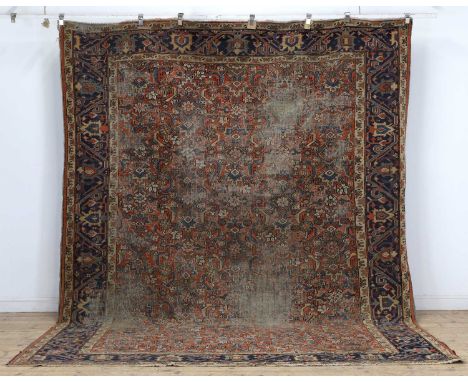 A North West Persian carpet, early to mid 20th century, with blue borders to a red ground, with foliate and geometric motifs,