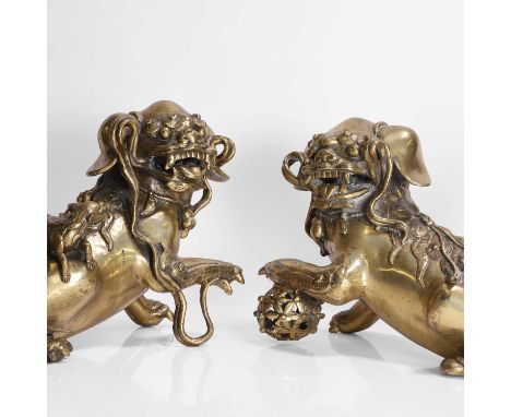 A pair of Chinese gilt-bronze Buddhist lions, 19th century, each modelled with bulging eyes beneath bushy brows, a knobbly sp