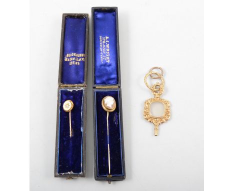 Two stick pins and a watch key, the highly decorative watch key having a chalcedony centre with a scroll and foliate frame, s