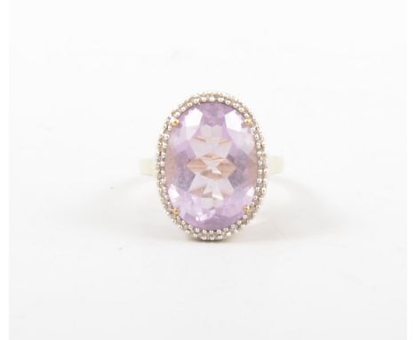 An amethyst and diamond dress ring, the oval mixed cut stone 18mm x 13mm, surrounded by small diamond points in a 9 carat yel