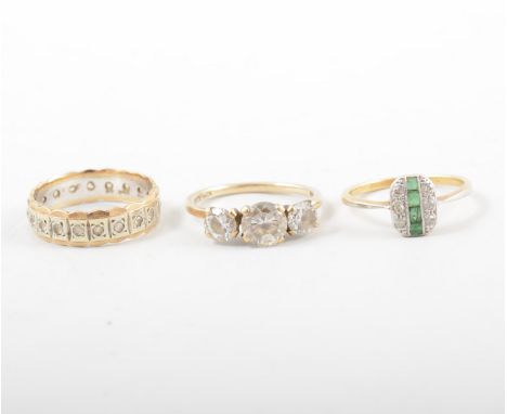 Three stone set rings, a rectangular pave set cluster with four small emeralds and six diamonds, yellow and white metal mount