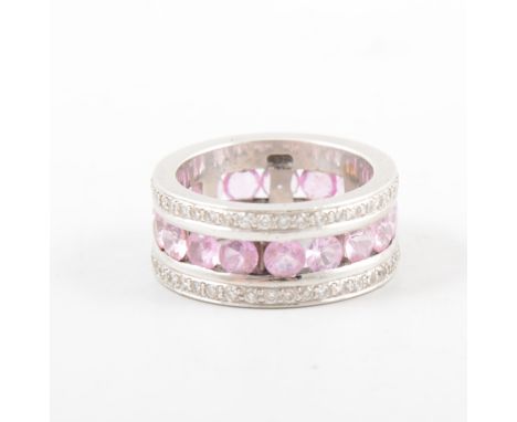 A full etermity ring, a band of pink stones bordered by a band of channel set diamonds to each side, in an all white metal mo