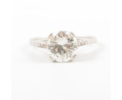 A diamond solitaire ring, the brilliant cut stone four claw set in an all white metal mount, finely etched shank with three s