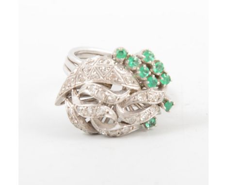 An emerald and diamond fancy cluster ring, nine small emeralds claw set and thirty small eight cut diamonds pave set in an al