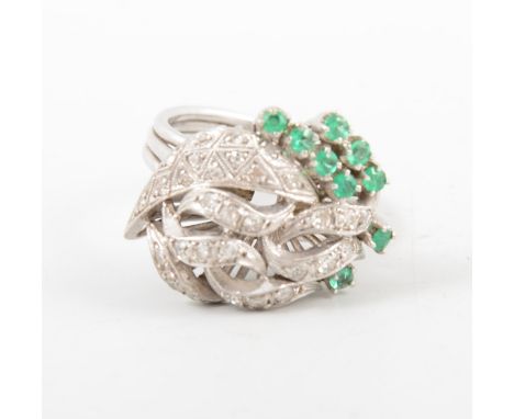 An emerald and diamond fancy cluster ring, nine small emeralds claw set and thirty small eight cut diamonds pave set in an al