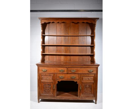 Victorian oak sideboard, adapted as a dresser with a later three shelf delft rack, the base with three drawers and two carved