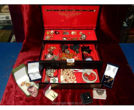 A black jewellery box containing clip on earrings, necklaces, jade and gold coloured earrings, brooches, bangles, etc.,