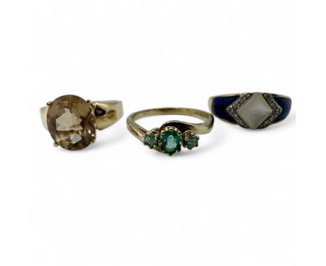 Three 9ct gold dress rings.  To include a mother of pearl, blue hardstone and diamond set ring, size S; an emerald three ston