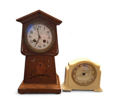 An Arts and crafts period oak cased mechanical chiming mantel clock with owl marquetry. with an inlaid moon and stars. Stands