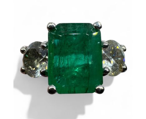 An emerald and diamond three stone ring in 18ct white gold. Set with a central octagon cut emerald, estimated carat weight 1.