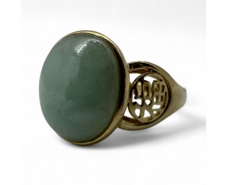 A 14ct gold jadeite set ring. Featuring a cabochon of pale mottled green jadeite to the centre. Featuring the Chinese charact