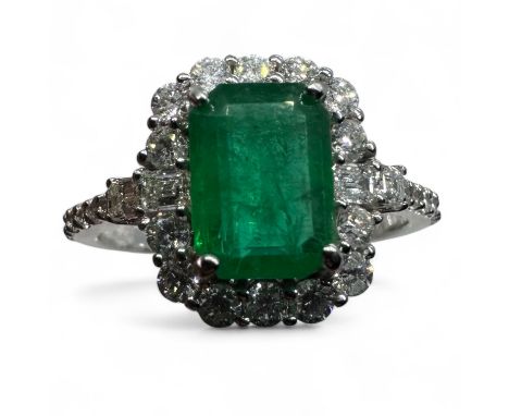 An 18ct white gold emerald and diamond ring. Featuring a step cut emerald of an estimated 1.40 carats, and surrounded by diam
