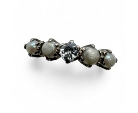 An early 20th century diamond and pearl half hoop ring. Set with a central 3.2mm average diameter old round cut diamond, and 