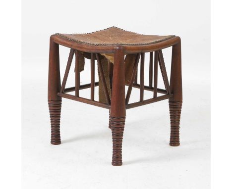 Attributed to Liberty & Co., an oak 'Thebes' stool, c.1880, with a leather and brass-studded seat, on tapering legs with carv