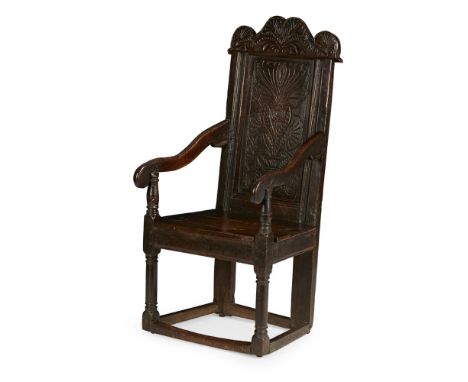 OAK WAINSCOT ARMCHAIR  17TH CENTURY   the arched cresting carved with flower motifs above a panel back carved with a flowerin