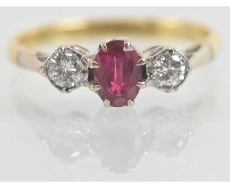 An 18ct yellow gold ruby and diamond set three stone ring, the central oval cut ruby approx 0.5ct, flanked by a pair of diamo