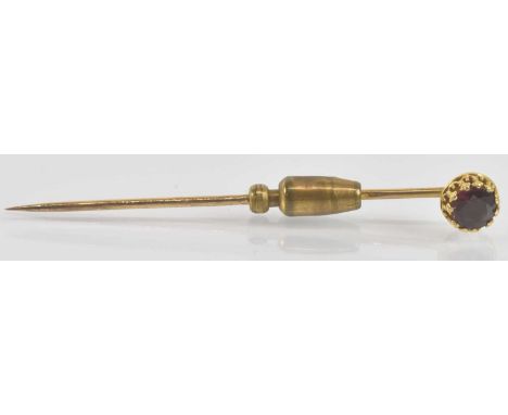 A yellow metal tie pin with claw set garnet, length 6.5cm, approx 2.6g.